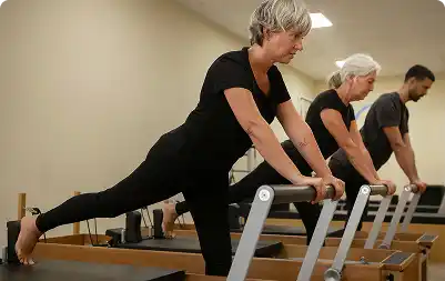 Idosos praticando alongamento no aparelho de reformer